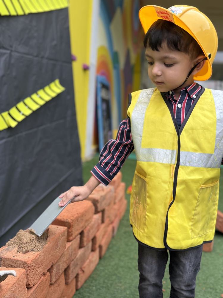 A boy laying bricks in a hard hat